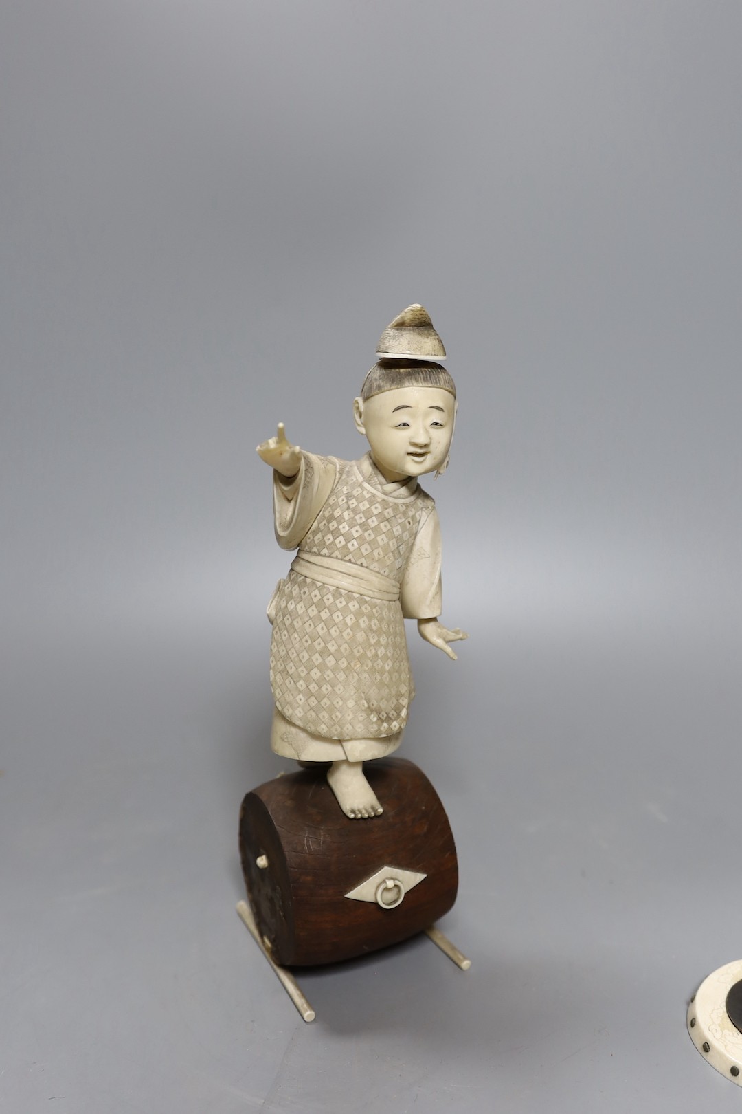 A 19th century Japanese ivory okimono, boy on a barrel with red seal to base, 24cm, together with two carved ivory counters